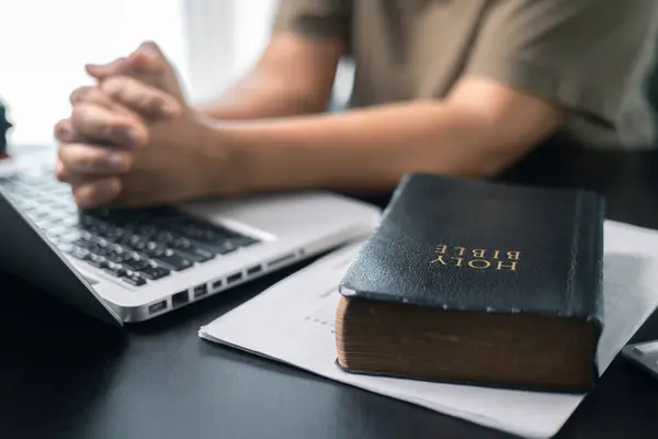 man sitting at computer with bible